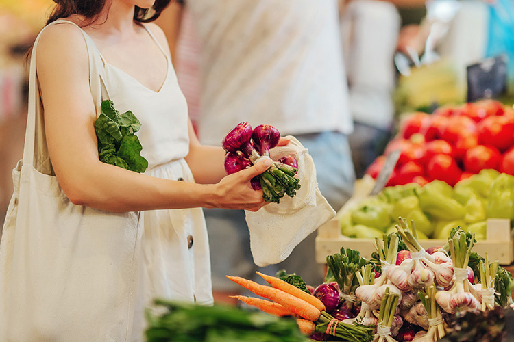 Una chica con vestido blanco compra fruta en el supermercado